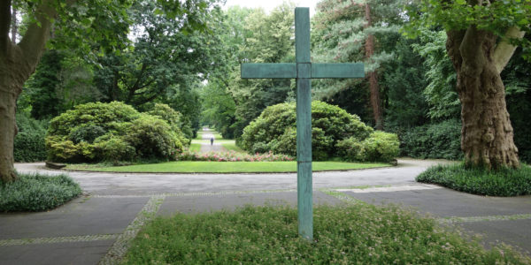 Hochkreuz im Eingangsbereich des Südfriedhofs in Ückendorf mit Blick auf die beidseitig von hohen Bäumen eingerahmte Hauptwegeachse.